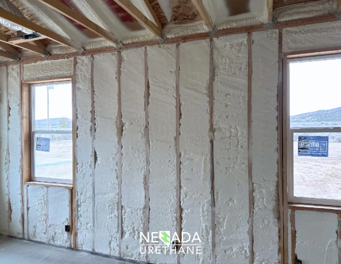 Interior wall and ceiling framing with spray foam insulation and two windows.